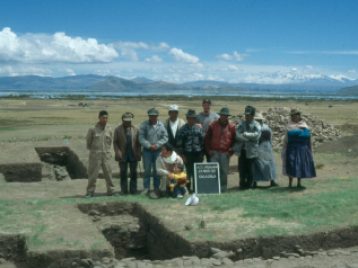 12 members of the work crew standing in between two excavated sections of Alto Pukara.